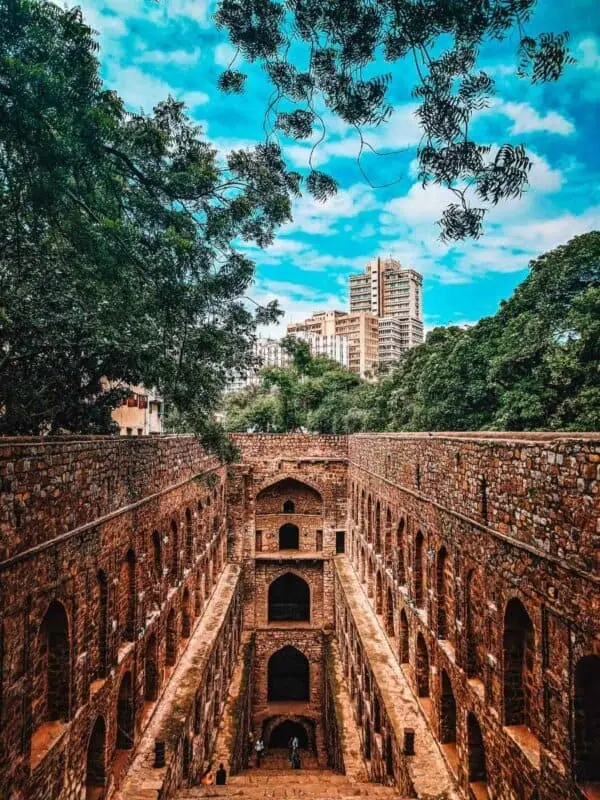 agrasen ki baoli stepwell in delhi with arched walls and city skyline in background
