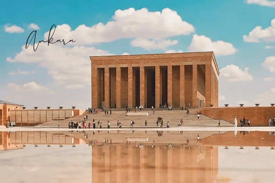 anıtkabir, the grand mausoleum of mustafa kemal atatürk, standing tall against a bright blue sky with visitors walking around the large courtyard