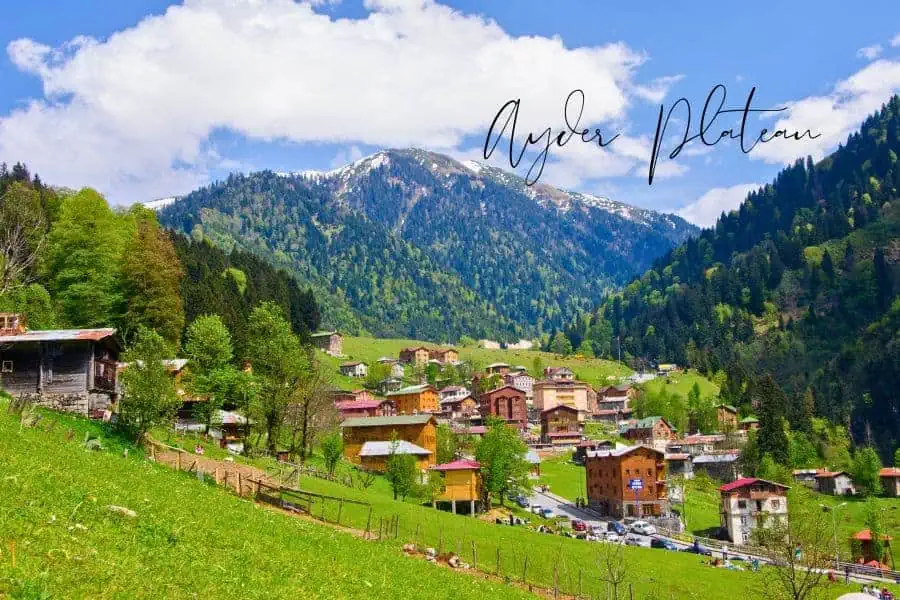 the lush green slopes and wooden houses of ayder plateau surrounded by misty mountains