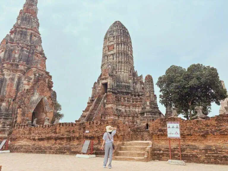 me standing near the ancient brick ruins of wat chaiwatthanaram in ayutthaya, thailand, wearing a hat and exploring the historic site