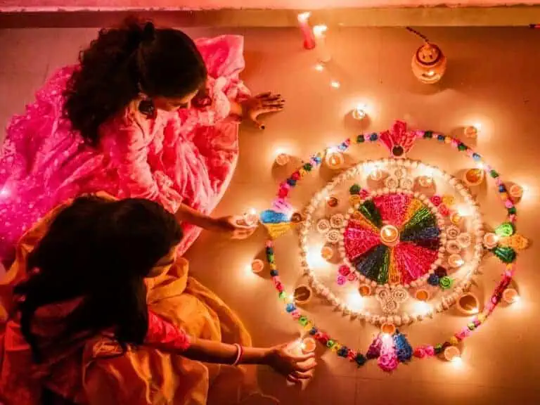 best light festivals round the world featured image two women lighting earthern diyas for diwali
