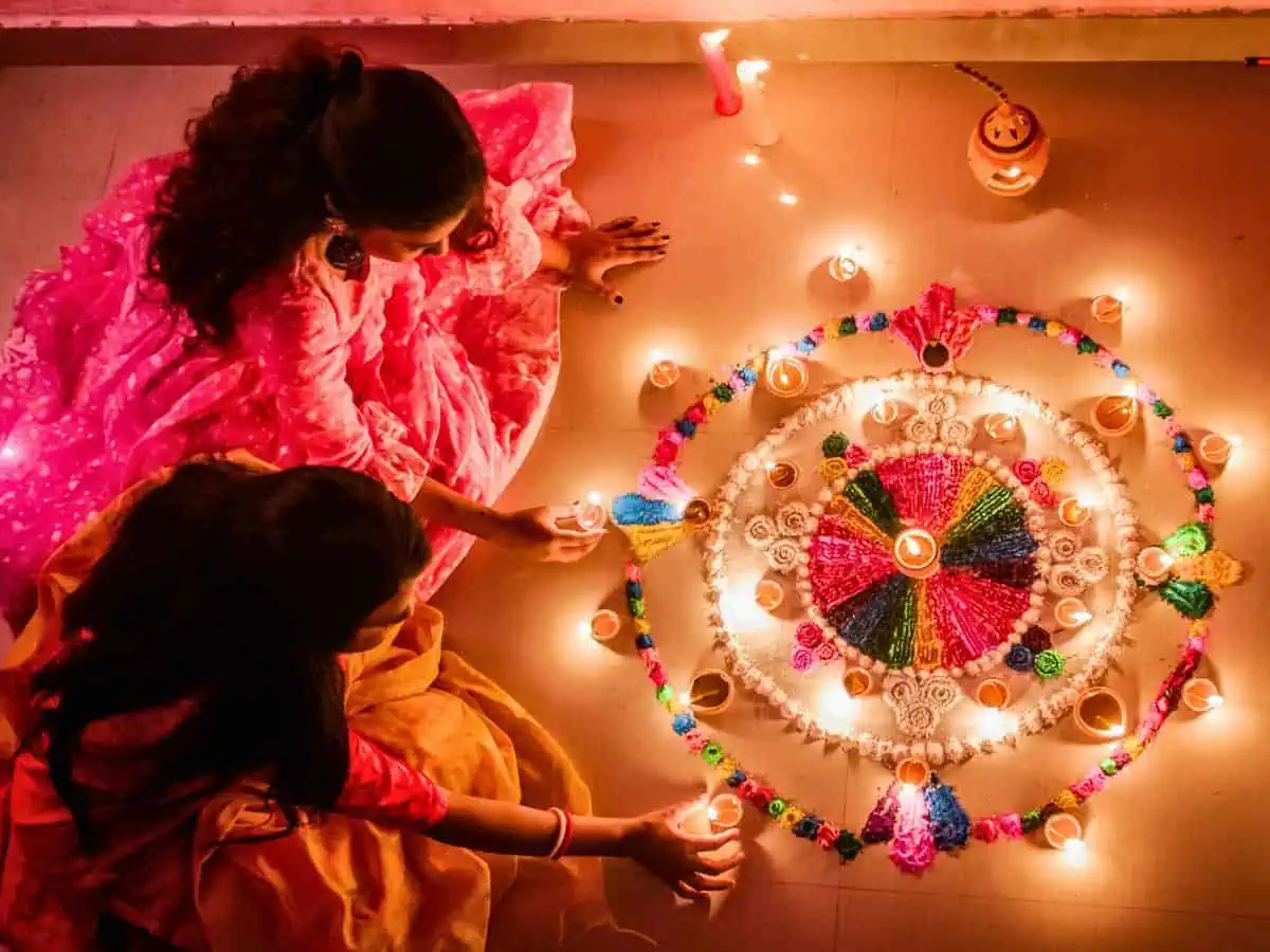 best light festivals round the world featured image two women lighting earthern diyas for diwali