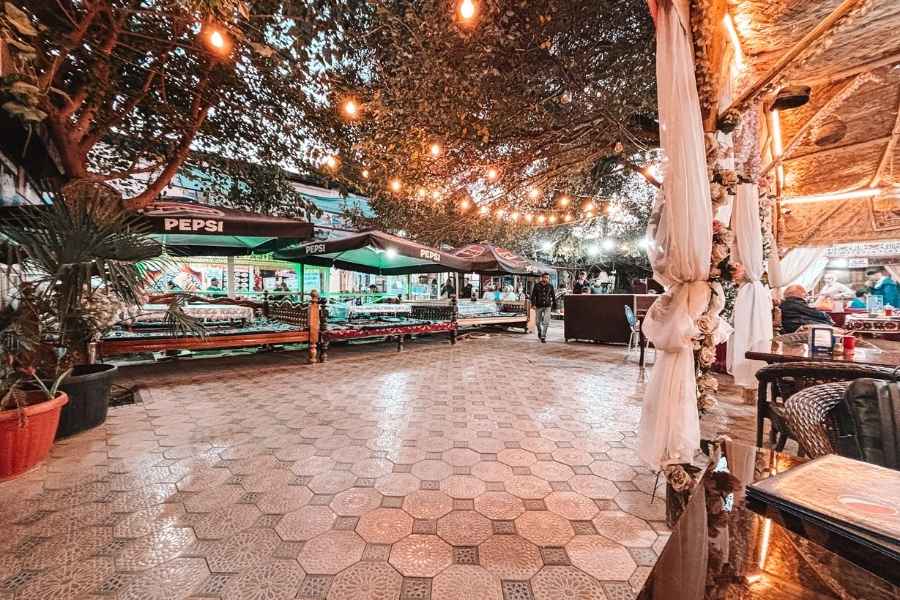 bibi khanym teahouse courtyard in samarkand with string lights, tiled floor, and outdoor seating under trees