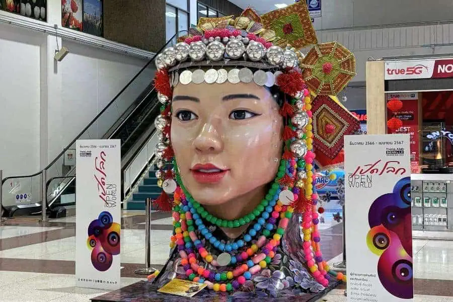 a colorful statue of a traditional thai woman's head with beads and coins at mae fah luang chiang rai international airport