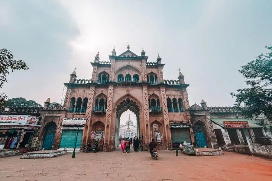 chota imambara entrance with old city shops and pedestrians, lucknow