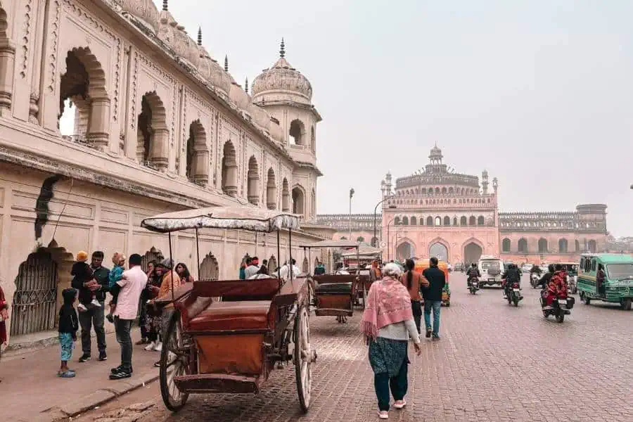 crowded street in hussainabad near bara imambara with tongas, pedestrians, and rumi darwaza in the background, lucknow