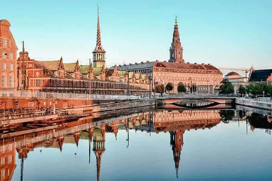the image showcasing stunning architecture of copenhagen mirrored in its serene waters for denmark itinerary