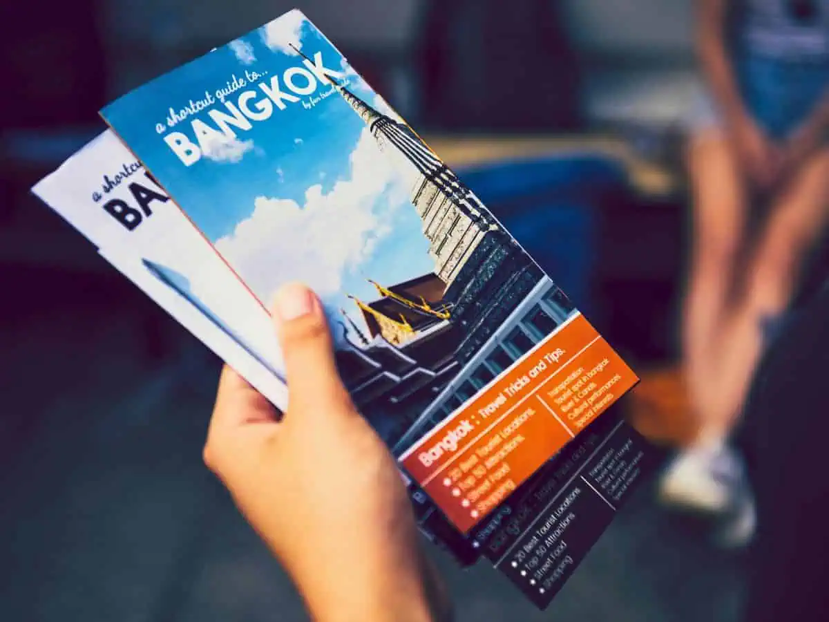 a tourist holding a travel guide brochure to know bangkok travel tips to make full use of first time in bangkok