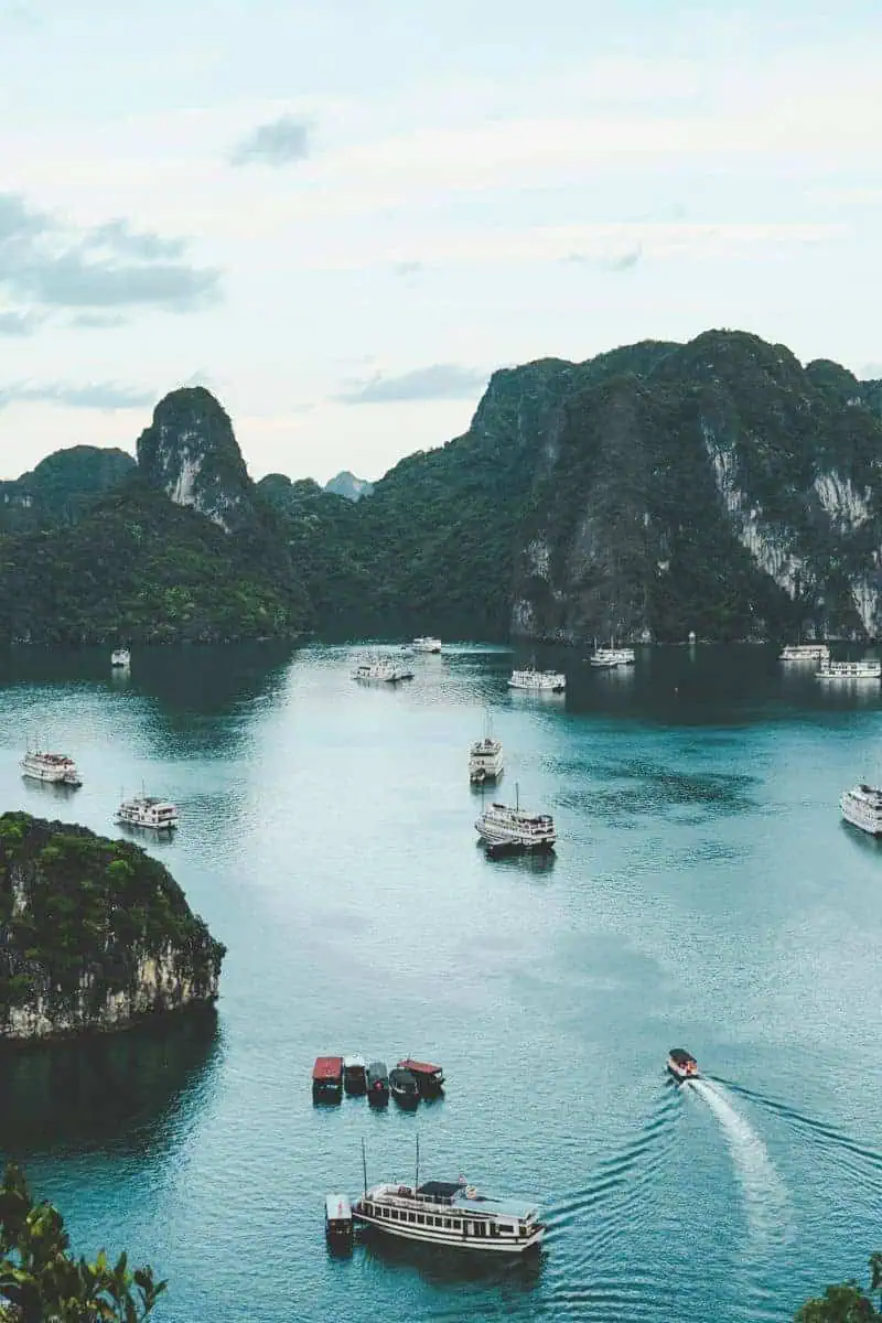 boats sailing through the emerald waters of ha long bay surrounded by towering limestone islands in vietnam