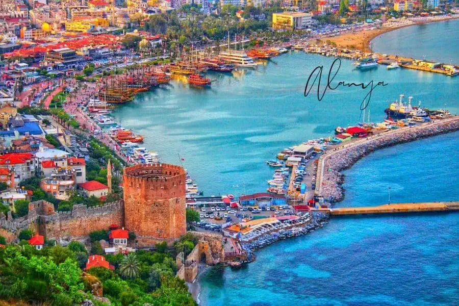 an aerial view of the stunning harbor, the historic Red Tower, and the turquoise coastline filled with boats