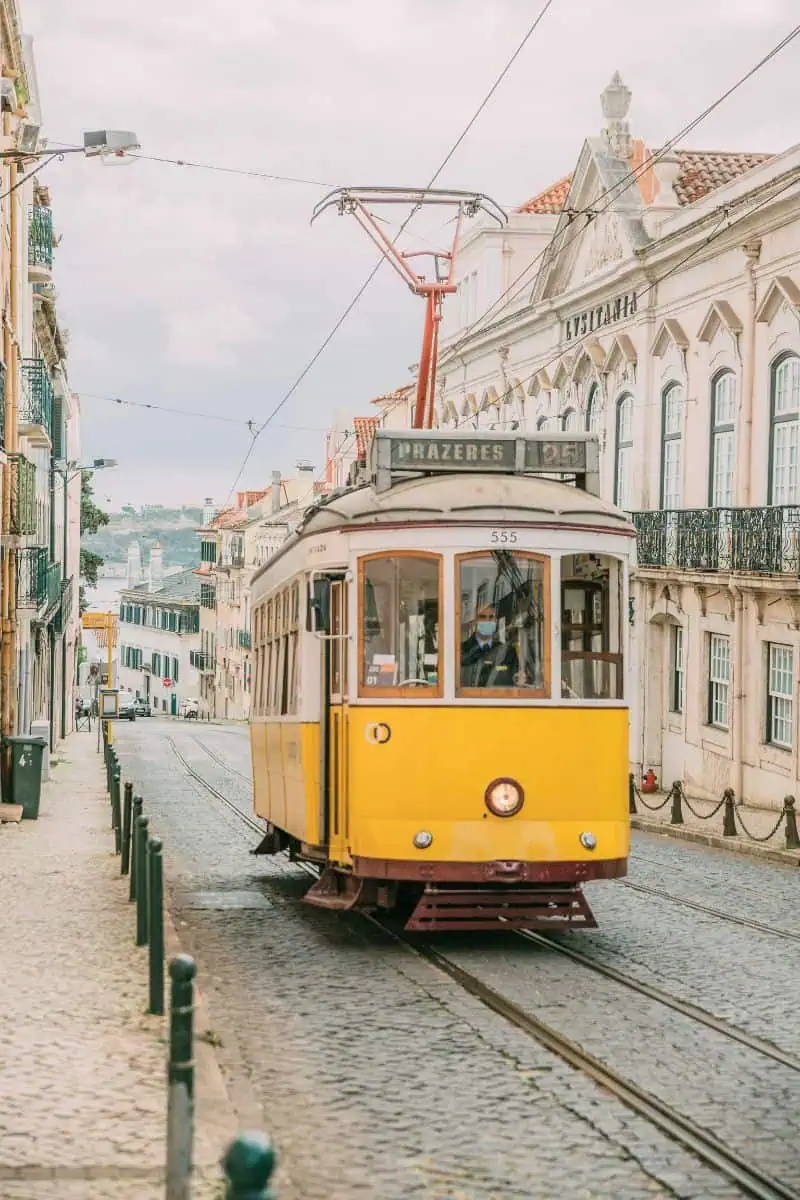 historic yellow tram number 28 passing through the narrow streets of lisbon, portugal
