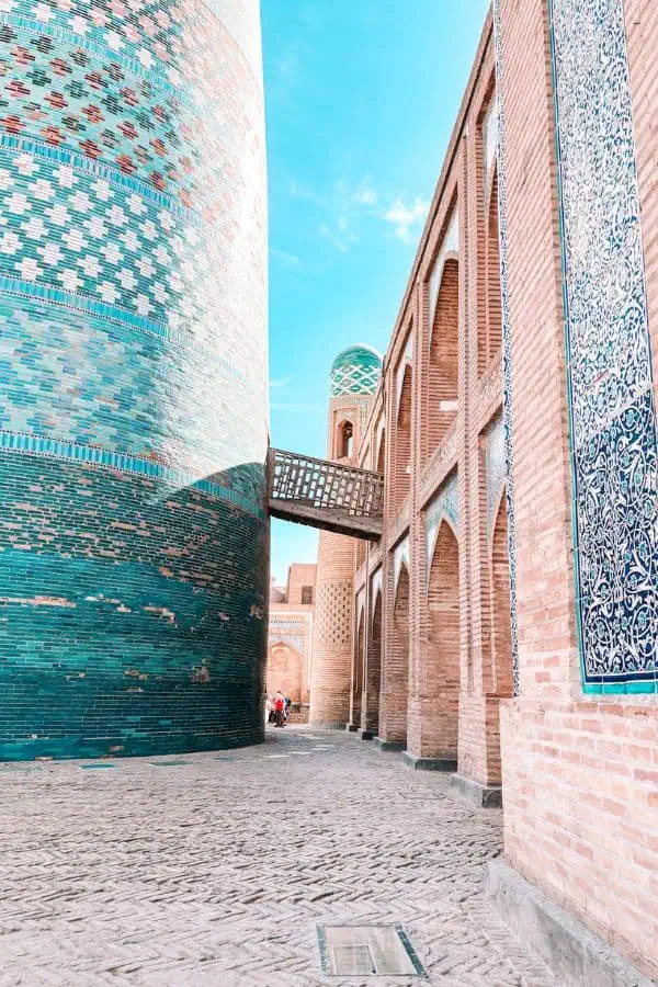 narrow alley between kalta minor minaret and madrasa in itchan kala khiva with blue tiles and brick arches