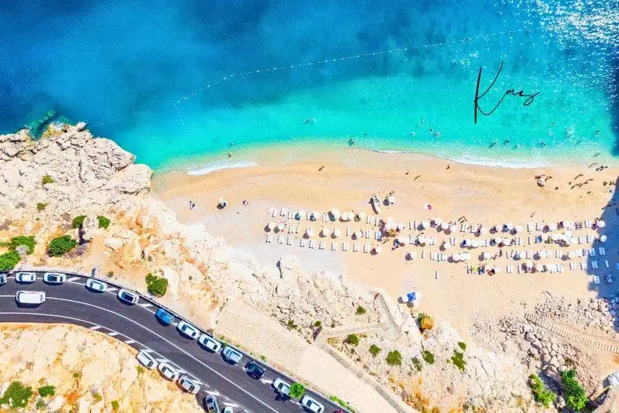 aerial view of kaputaş beach near kaş, where golden sand meets the turquoise waters of the mediterranean, lined with sunbathers and umbrellas