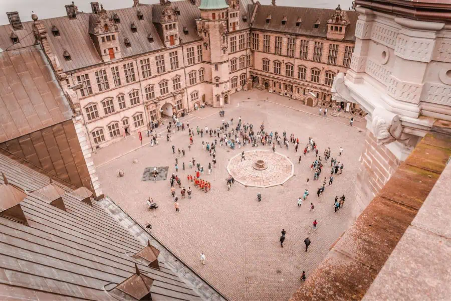 An aerial view of Kronborg Castle's cobblestone courtyard in Helsingør, with tourists gathered below — Shakespeare's Hamlet was set in this very castle