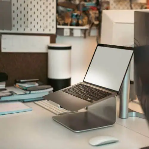 modern desktop setup with a laptop on a stand, external monitor, keyboard, and mouse on a white desk