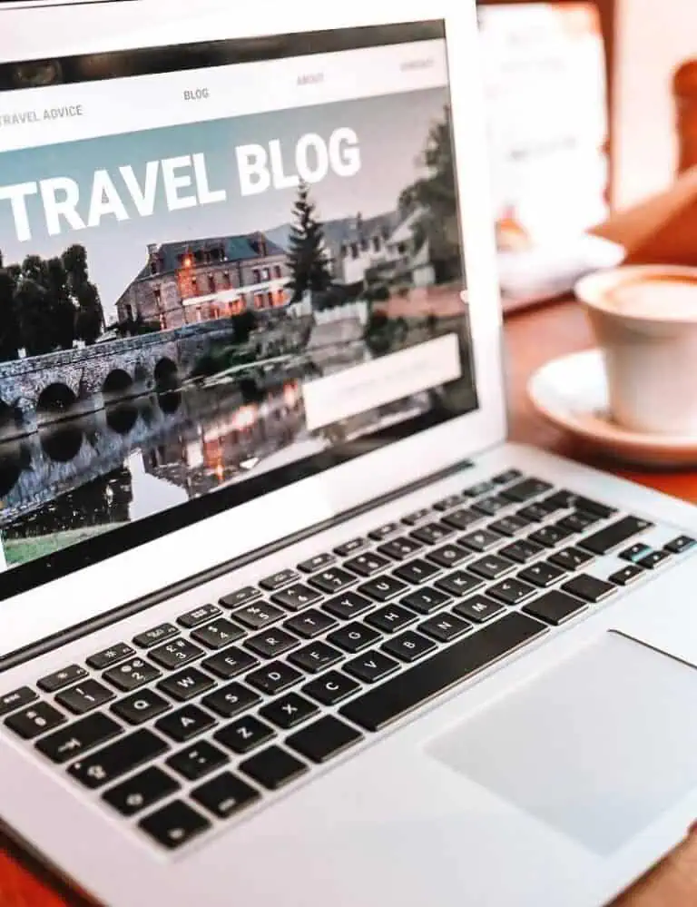 laptop showing a travel blog with a cup of coffee on its side