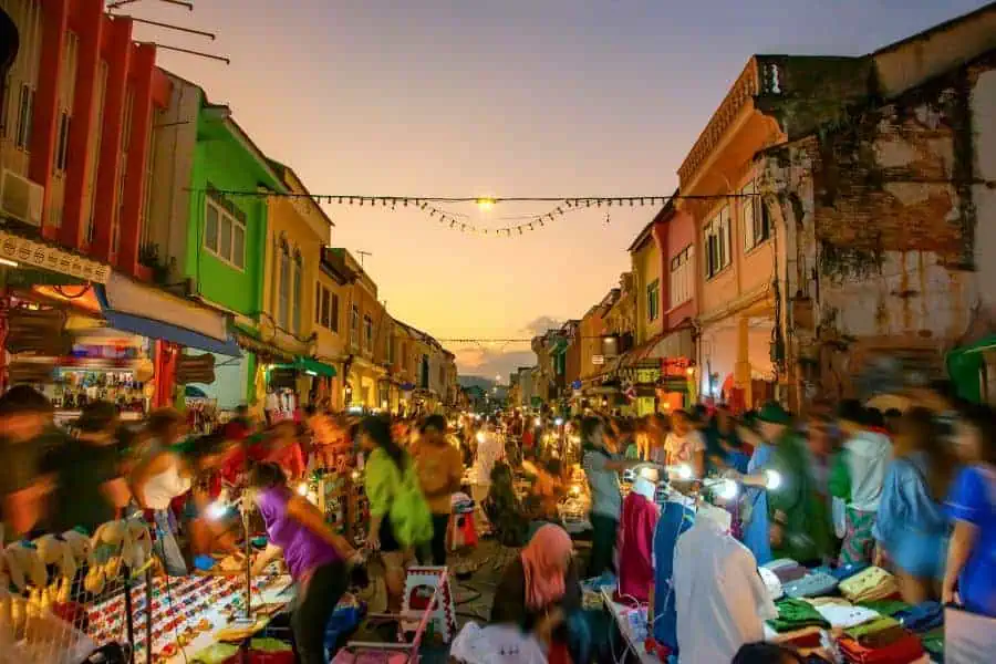 phuket sunday night market on thalang road in old town, bustling with colorful stalls, food vendors, and crowds under warm sunset lights