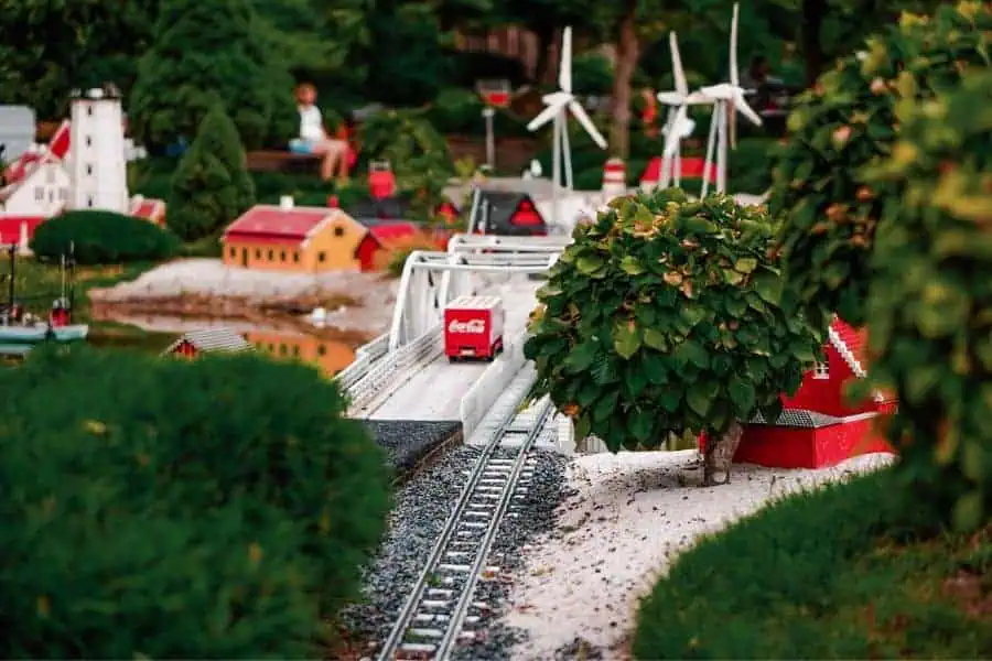 A miniature Lego landscape at Legoland Billund featuring a red bridge, lighthouse, and Coca-Cola truck — the original Legoland and a must-visit stop on a family Denmark itinerary