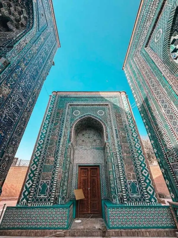 ornate turquoise tiled mausoleum at shakhi zinda ensemble in samarkand framed by richly decorated walls under a clear blue sky