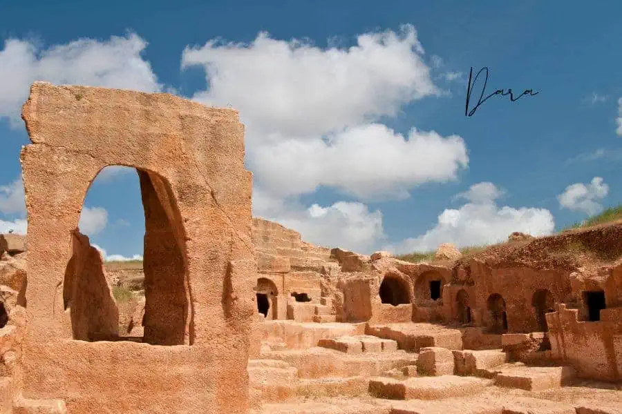 ancient rock-carved structures of dara with a bright blue sky and scattered clouds