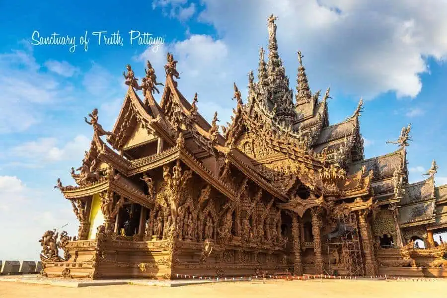 intricately carved wooden sanctuary of truth in pattaya, thailand, with elaborate traditional thai architecture set against a blue sky