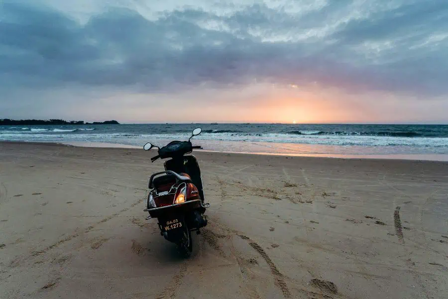 scooter parked on a quiet goa beach at sunset with waves in the background