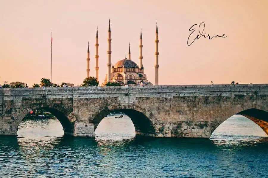 a stunning view of the selimiye mosque and an old stone bridge over the river at sunset in edirne, turkey