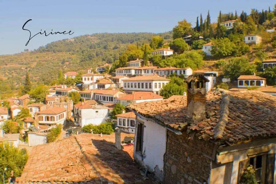 a charming hillside village with red-roofed houses nestled among green vineyards and cypress trees
