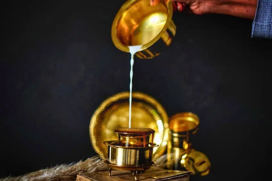 south indian filter coffee pouring between traditional brass vessels