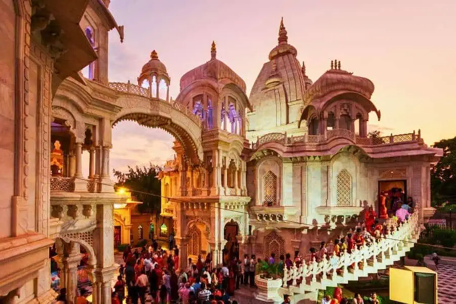 sri sri krishna balaram mandir or iskcon temple in vrindavan lit up at dusk with visitors on the marble steps