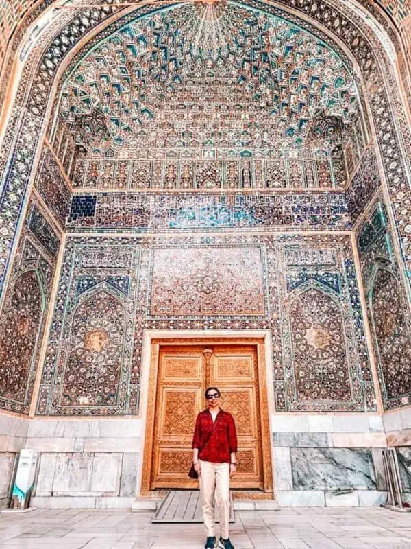 Faraway Notes author blogger standing in front of ornate tiled iwan inside ulugh beg madrasah at registan square