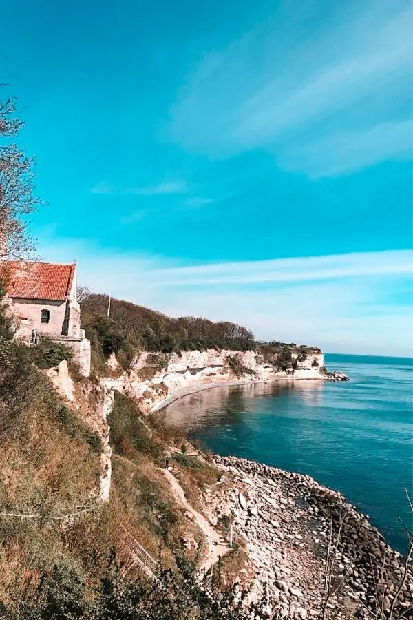 Stevns Klint chalk cliffs with a small historic church perched at the edge overlooking the sea — a UNESCO World Heritage Site in Denmark