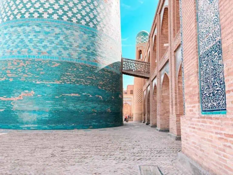 turquoise-tiled minaret and brick walls in khiva, uzbekistan under a clear blue sky
