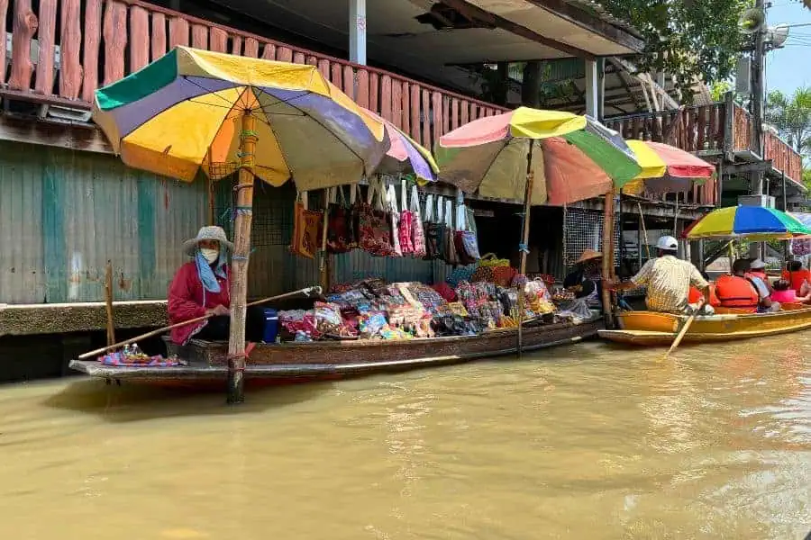vendors selling items or souvenirs in their boats at damnoen saduak floating market