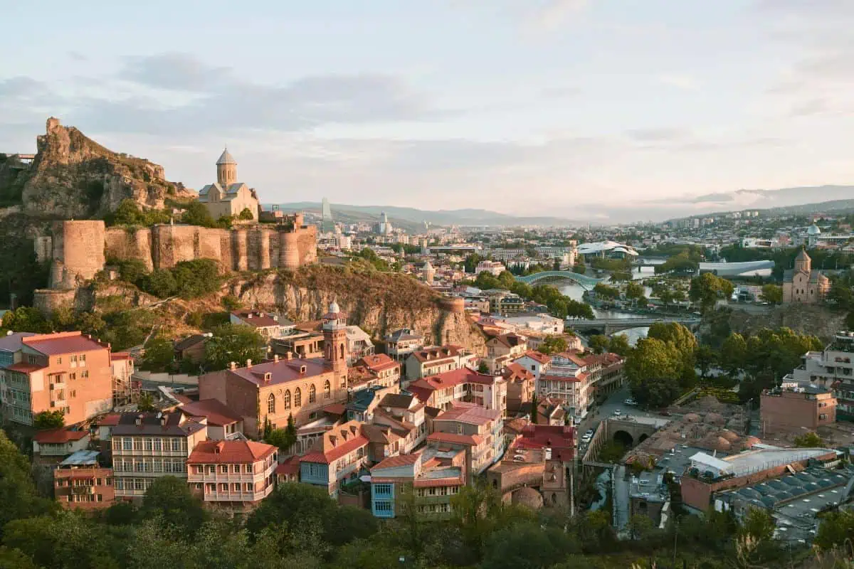view of narikala fortress and old town tbilisi with colorful houses and peace bridge in the distance