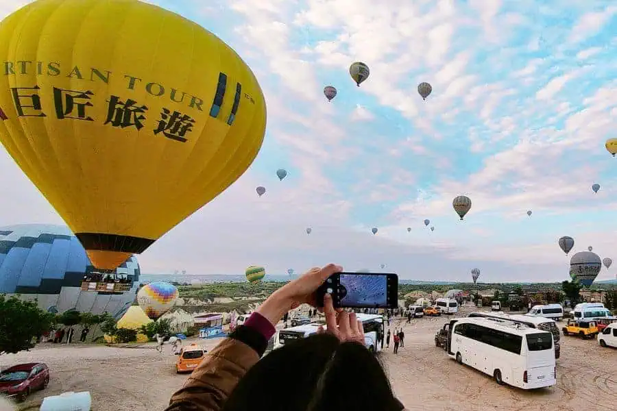 visitors capturing and watching hot air balloons from love valley viewpoint