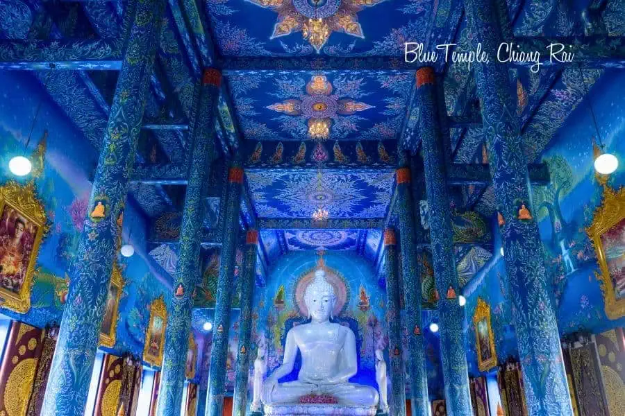 vibrant blue interior of the blue temple (wat rong suea ten) in chiang rai, thailand, featuring intricate murals, ornate decorations, and a striking white buddha statue